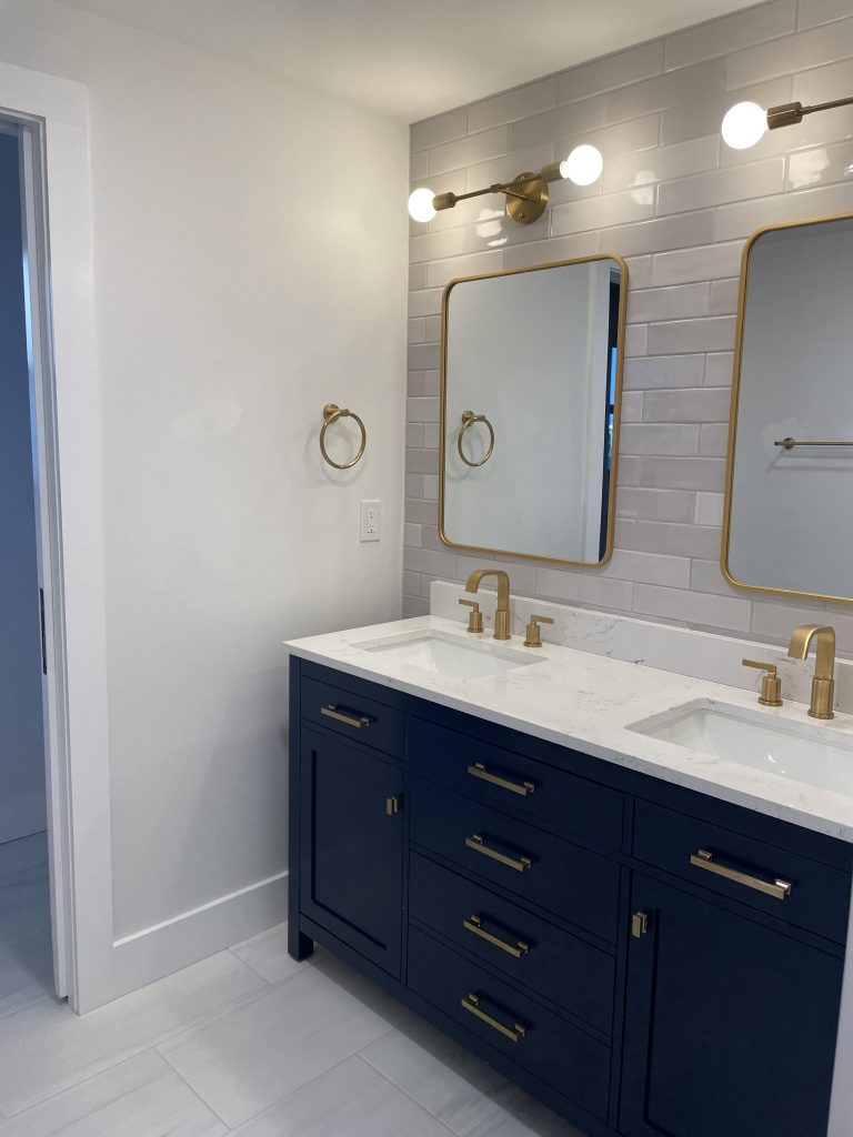 Navy blue double vanity with brass fixtures and a white countertop