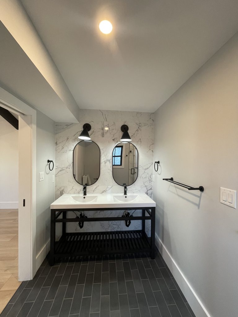 Bathroom with a double vanity, oval mirrors and marble-look tile