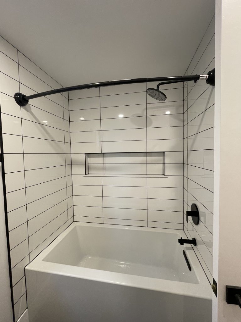 Tub and shower with white subway tile and a built-in niche